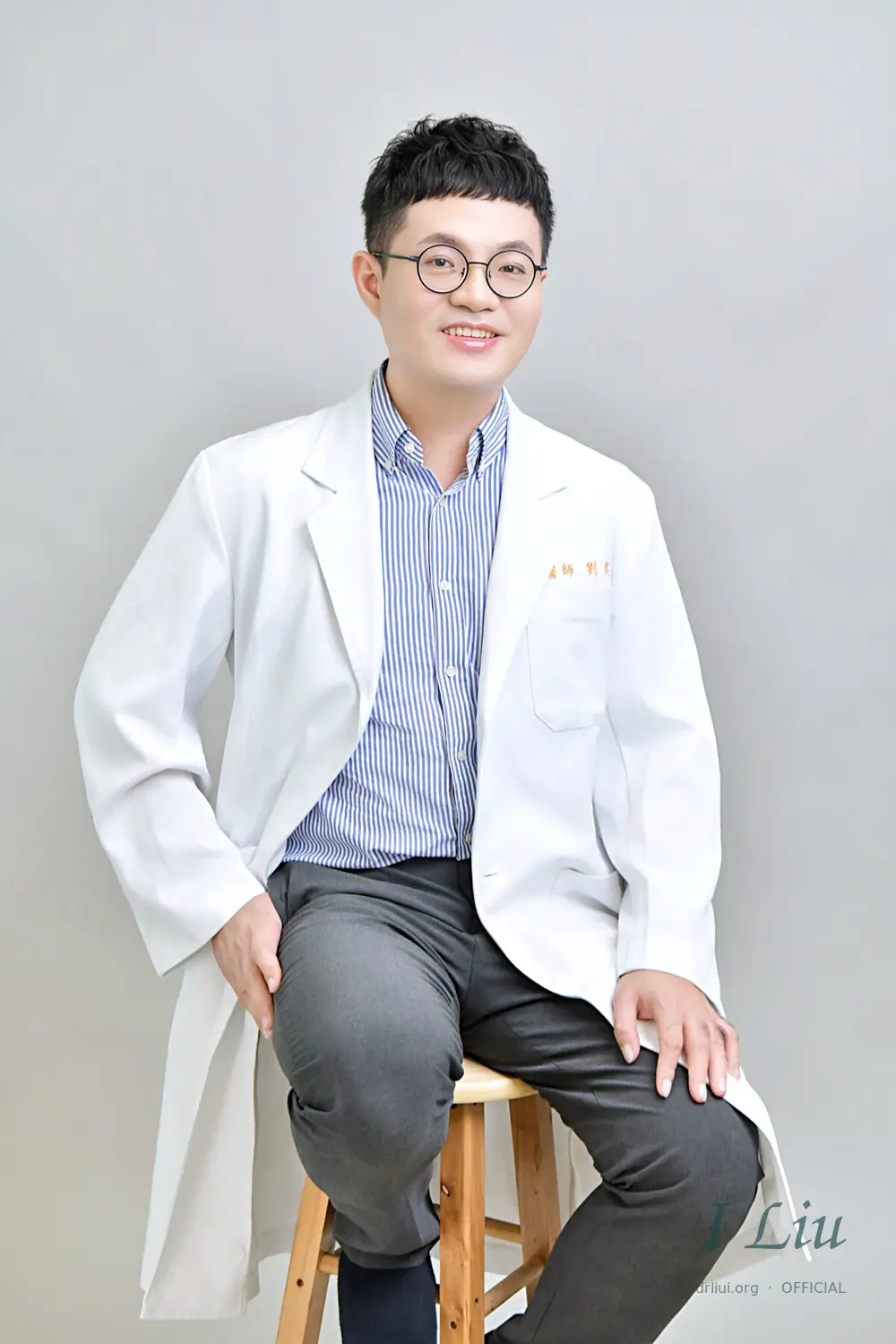 劉奕醫師白袍坐姿形象照；照片標示 I Liu 簽名式官方網站浮水印